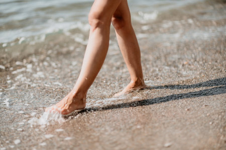 A woman walks along the beach, legs close-up. Barefoot woman sta