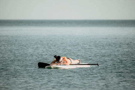 Sea woman sup. Silhouette of happy middle aged woman in rainbowの写真素材