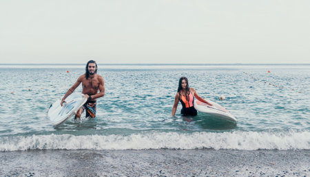 Sea woman and man on sup. Silhouette of happy young woman and man, surfing on SUP board, confident paddling through water surface. Idyllic sunset. Active lifestyle at sea or river.の写真素材