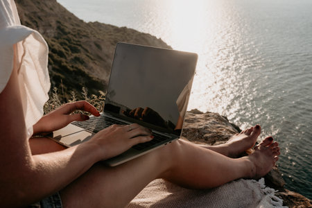 Woman sea laptop. Business woman working on laptop by sea at sunset. Close up on hands of pretty lady typing on computer outdoors summer day. Freelance, digital nomad, travel and holidays concept.の写真素材
