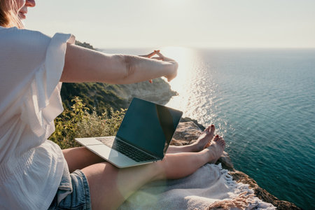 Woman sea laptop. Business woman working on laptop by sea at sunset. Close up on hands of pretty lady typing on computer outdoors summer day. Freelance, digital nomad, travel and holidays concept.の写真素材