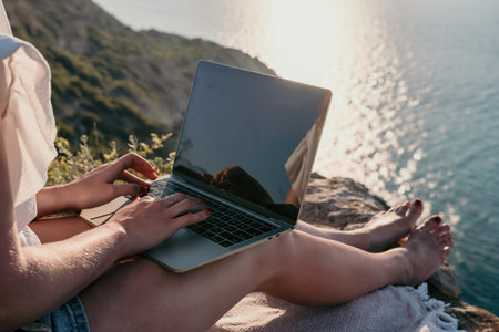 Woman sea laptop. Business woman working on laptop by sea at sunset. Close up on hands of pretty lady typing on computer outdoors summer day. Freelance, digital nomad, travel and holidays concept.の写真素材