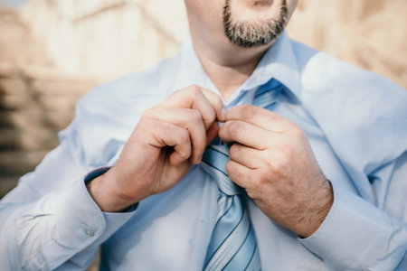 Close up of Man Adjusting Tie of Suit. Businessman in blue shirt straightens his tie, close-upの写真素材