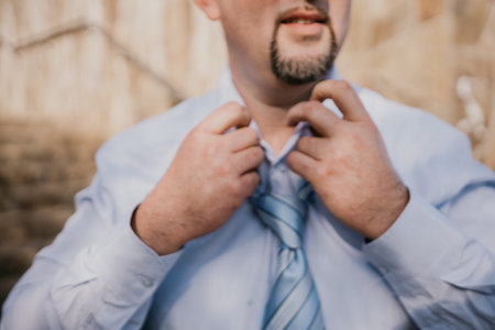 Close up of Man Adjusting Tie of Suit. Businessman in blue shirt straightens his tie, close-upの写真素材