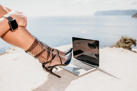 Woman sea laptop. Business woman in yellow hat freelancer with laptop working over blue sea beach. Girl relieves stress from work. Freelance, digital nomad, travel and holidays conceptの写真素材