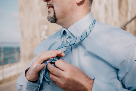 Close up of Man Adjusting Tie of Suit. Businessman in blue shirt straightens his tie, close-upの写真素材