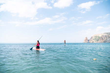 Woman sup yoga. Happy young sporty woman practising yoga pilates on paddle sup surfboard. Female...