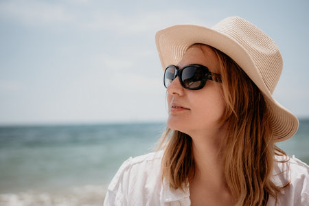 Young woman in red bikini on Beach. Blonde in sunglasses on pebble beach enjoying sun. Happy lady in one piece red swimsuit relaxing and sunbathing by turquoise sea ocean on hot summer day. Close upの写真素材