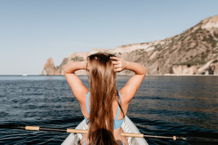 Woman in kayak back view. Happy young woman with long hair floating in kayak on calm sea. Summer...