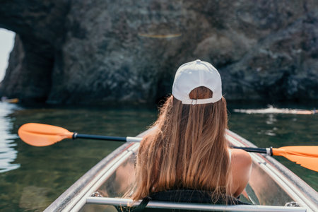 Woman in kayak back view. Happy young woman with long hair floating in transparent kayak on the crystal clear sea. Summer holiday vacation and cheerful female people relaxing having fun on the boatの写真素材