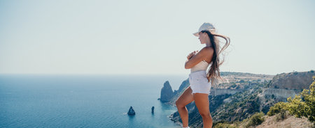 Woman summer travel sea. Happy tourist enjoy taking picture outdoors for memories. Woman traveler posing over sea bay surrounded by volcanic mountains, sharing travel adventure journeyの写真素材