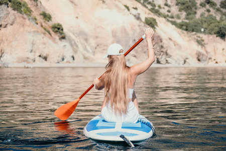 Woman sea sup. Close up portrait of happy young caucasian woman with long hair looking at camera and smiling. Cute woman portrait in bikini posing on sup board in the seaの写真素材
