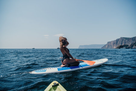 Woman sea sup. Close up portrait of happy young caucasian woman with long hair looking at camera and smiling. Cute woman portrait in bikini posing on sup board in the seaの写真素材