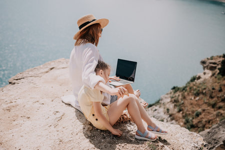 Woman sea laptop. Successful business woman working on laptop by the sea. Pretty lady typing on computer at summer day outdoors. Freelance, digital nomad, travel and holidays concept.の写真素材