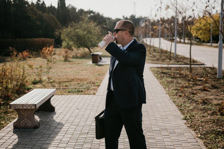 Mature entrepreneur drink coffee in autumn park. Senior executive rest in city park.の写真素材