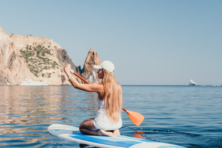 Woman sea sup. Close up portrait of happy young caucasian woman with long hair looking at camera and smiling. Cute woman portrait in bikini posing on sup board in the seaの写真素材