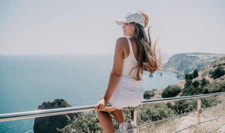 Woman summer travel sea. Happy tourist enjoy taking picture outdoors for memories. Woman traveler posing over sea bay surrounded by volcanic mountains, sharing travel adventure journeyの写真素材
