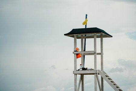 Empty white lifeguard tower with a yellow flag on the beach in windy weather. Beach lifeguard tower with yellow flag indicator. Nobody. Holiday recreation concept.の写真素材