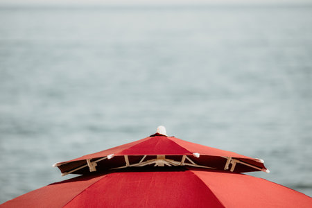 Red Beach Umbrella on the Background of the Blue Sea Ocean. Beach Landscape. Summer travel and holidays concept.の写真素材