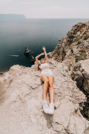 Woman travel sea. Young Happy woman posing on a beach over the sea on background of volcanic rocks, like in Iceland, sharing travel adventure journeyの写真素材