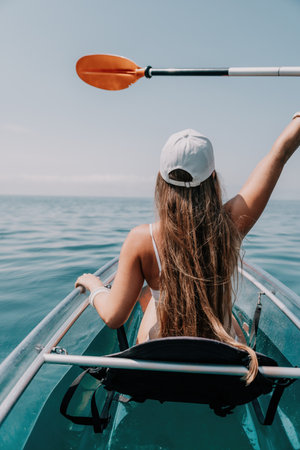 Woman in kayak back view. Happy young woman with long hair floating in transparent kayak on the...