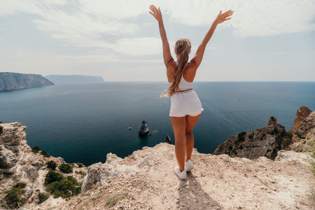 Woman travel sea. Young Happy woman posing on a beach over the sea on background of volcanic rocks, like in Iceland, sharing travel adventure journeyの写真素材