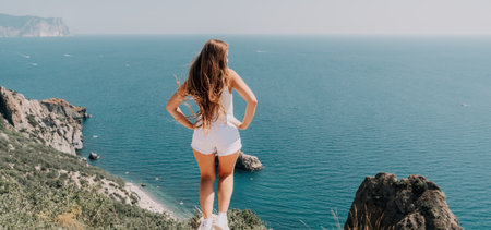 Woman summer travel sea. Happy tourist enjoy taking picture outdoors for memories. Woman traveler posing over sea bay surrounded by volcanic mountains, sharing travel adventure journeyの写真素材