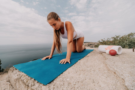 Woman sea pilates. Sporty, middle-aged woman practicing pilates in park near the sea. trains on a yoga mat and exudes a happy and active demeanor. healthy lifestyle through exercise and meditation.の写真素材