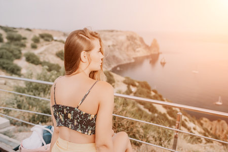 Woman travel sea. Happy tourist enjoy taking picture outdoors for memories. Woman traveler looks at the edge of the cliff on the sea bay of mountains, sharing travel adventure journeyの写真素材
