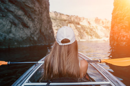 Woman in kayak back view. Happy young woman with long hair floating in transparent kayak on the crystal clear sea. Summer holiday vacation and cheerful female people relaxing having fun on the boatの写真素材