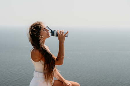 Woman summer travel sea. Happy tourist enjoy taking picture outdoors for memories. Woman traveler posing over sea bay surrounded by volcanic mountains, sharing travel adventure journeyの写真素材