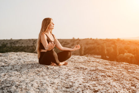 Fitness woman. Well looking middle aged woman with long hair, fitness instructor in leggings and tops doing stretching and pilates on the rock near forest. Female fitness yoga routine concept.の写真素材