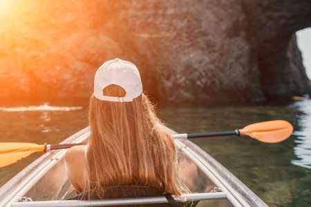 Woman in kayak back view. Happy young woman with long hair floating in transparent kayak on the crystal clear sea. Summer holiday vacation and cheerful female people relaxing having fun on the boatの写真素材