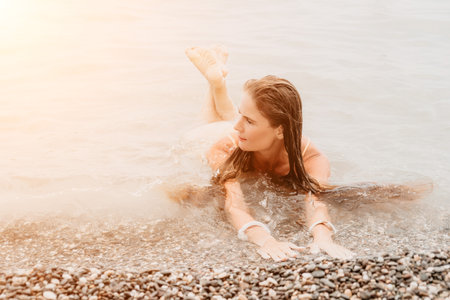 Woman travel sea. Happy tourist in hat enjoy taking picture outdoors for memories. Woman traveler posing on the beach at sea surrounded by volcanic mountains, sharing travel adventure journeyの写真素材
