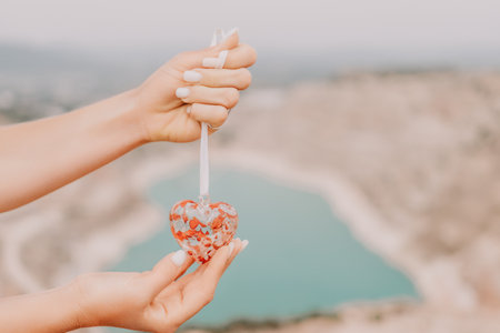 Woman travel portrait. Happy woman with long hair looking at camera and smiling. Close up portrait cute woman is posing on a heart shaped lake - travel destinationの写真素材