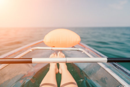 Woman in kayak back view. Happy young woman with long hair floating in transparent kayak on the crystal clear sea. Summer holiday vacation and cheerful female people relaxing having fun on the boatの写真素材