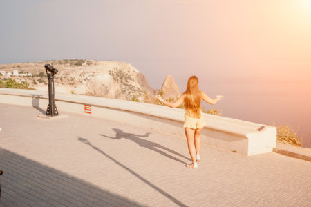 Woman summer dance. Silhouette of a happy woman who dances, spins and raises her hands to the sky. A playful young woman enjoys her happy moment dancing in the rays of the golden sun.の写真素材