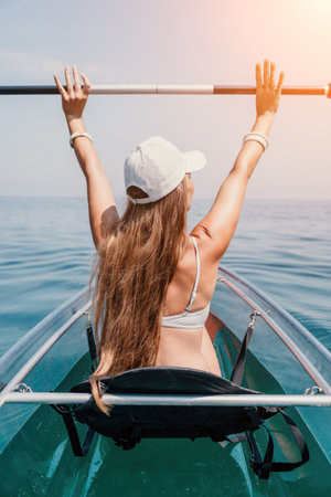 Woman in kayak back view. Happy young woman with long hair floating in transparent kayak on the crystal clear sea. Summer holiday vacation and cheerful female people relaxing having fun on the boatの写真素材
