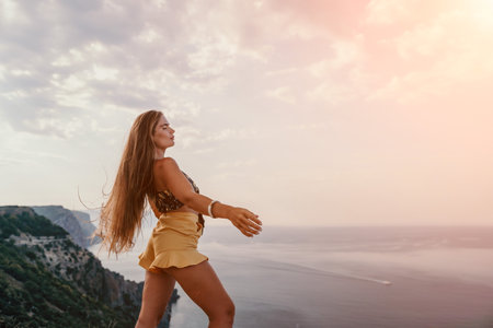 Woman travel sea. Happy tourist taking picture outdoors for memories. Woman traveler looks at the edge of the cliff on the sea bay of mountains, sharing travel adventure journeyの写真素材