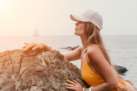 Woman travel sea. Happy tourist in hat enjoy taking picture outdoors for memories. Woman traveler posing on the beach at sea surrounded by volcanic mountains, sharing travel adventure journeyの写真素材