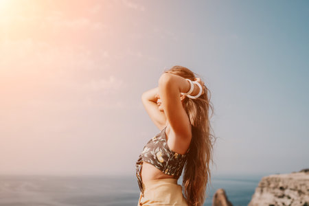 Woman travel sea. Happy tourist taking picture outdoors for memories. Woman traveler looks at the edge of the cliff on the sea bay of mountains, sharing travel adventure journeyの写真素材
