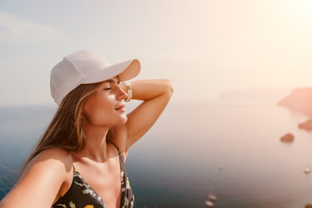 Woman travel sea. Happy tourist taking picture outdoors for memories. Woman traveler looks at the edge of the cliff on the sea bay of mountains, sharing travel adventure journeyの写真素材
