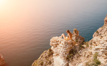 Woman travel sea. Happy tourist enjoy taking picture outdoors for memories. Woman traveler looks at the edge of the cliff on the sea bay of mountains, sharing travel adventure journeyの写真素材
