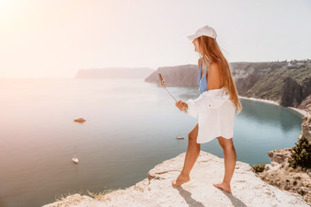 Digital nomad, Business woman working on laptop by the sea. Pretty lady typing on computer by the sea at sunset, makes a business transaction online from a distance. Freelance, remote work on vacationの写真素材