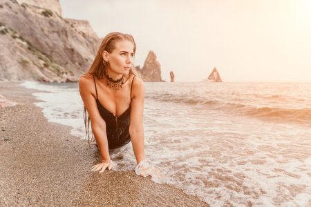 Woman summer travel sea. Happy tourist in black dress enjoy taking picture outdoors for memories. Woman traveler posing on sea beach surrounded by volcanic mountains, sharing travel adventure journeyの写真素材