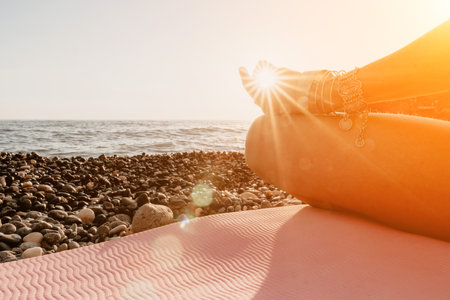 Woman sea yoga. Happy woman in white swimsuit and boho style braclets practicing outdoors on yoga mat by sea on sunset. Women yoga fitness routine. Healthy lifestyle, harmony and meditationの写真素材