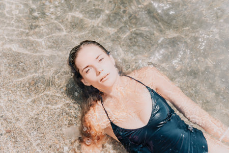 Woman summer travel sea. Happy tourist enjoy taking picture outdoors for memories. Woman traveler posing on the beach at sea surrounded by volcanic mountains, sharing travel adventure journeyの写真素材