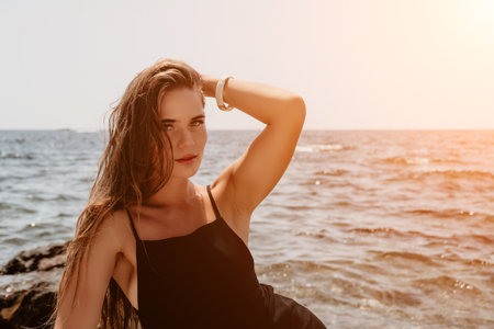 Woman summer travel sea. Happy tourist in hat enjoy taking picture outdoors for memories. Woman traveler posing on the beach at sea surrounded by volcanic mountains, sharing travel adventure journeyの写真素材