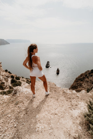 Woman travel sea. Young Happy woman posing on a beach over the sea on background of volcanic rocks, like in Iceland, sharing travel adventure journeyの写真素材