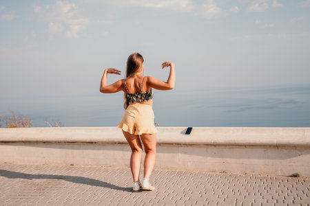 Woman summer dance. Silhouette of a happy woman who dances, spins and raises her hands to the sky. A playful young woman enjoys her happy moment dancing in the rays of the golden sun.の写真素材